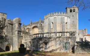 The Convent of Christ seen from the garden: the round Templar rotunda, crowned with battlements, adjoining the Manueline church and its balustraded terrace.